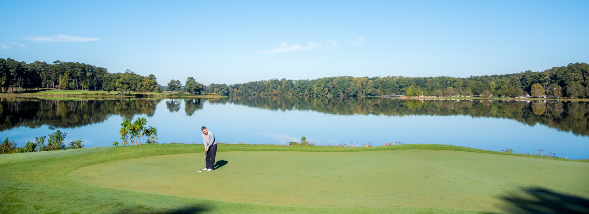 Man Putting Golf Ball with at Cobblestone Golf Course with Lake Acworth in the Background on a Sunny Day