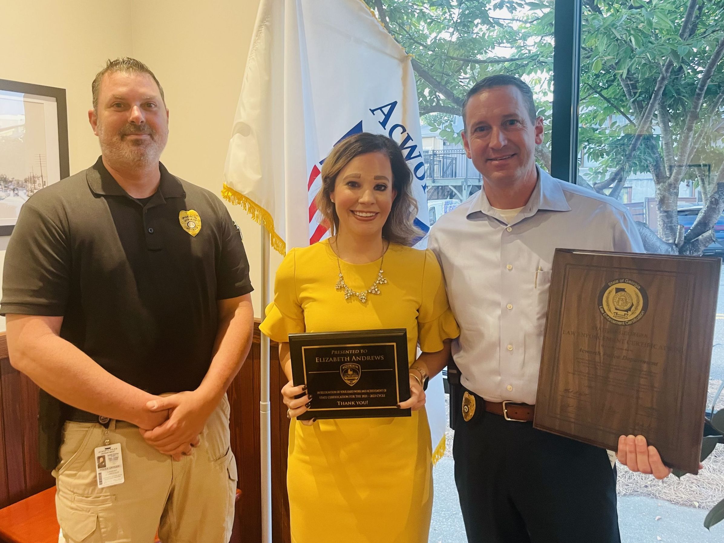 Image of three people from the Acworth Police Department holding two awards at Acworth City Hall