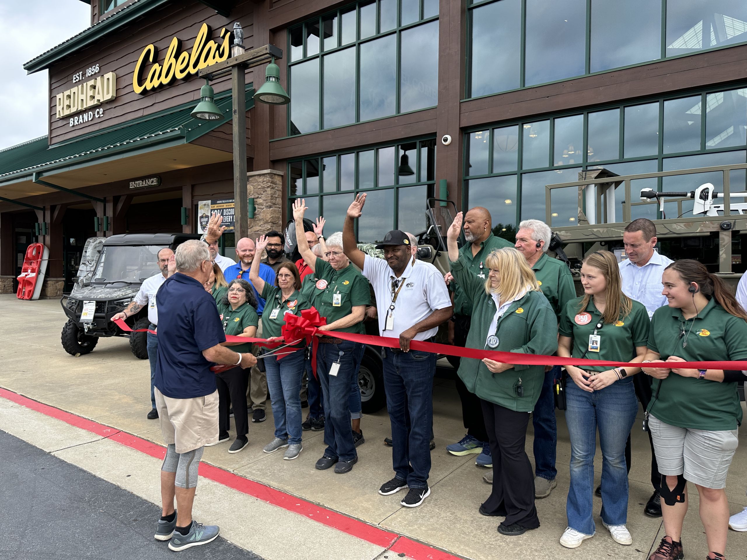 Image a group of people at a ribbon cutting outside of a large building