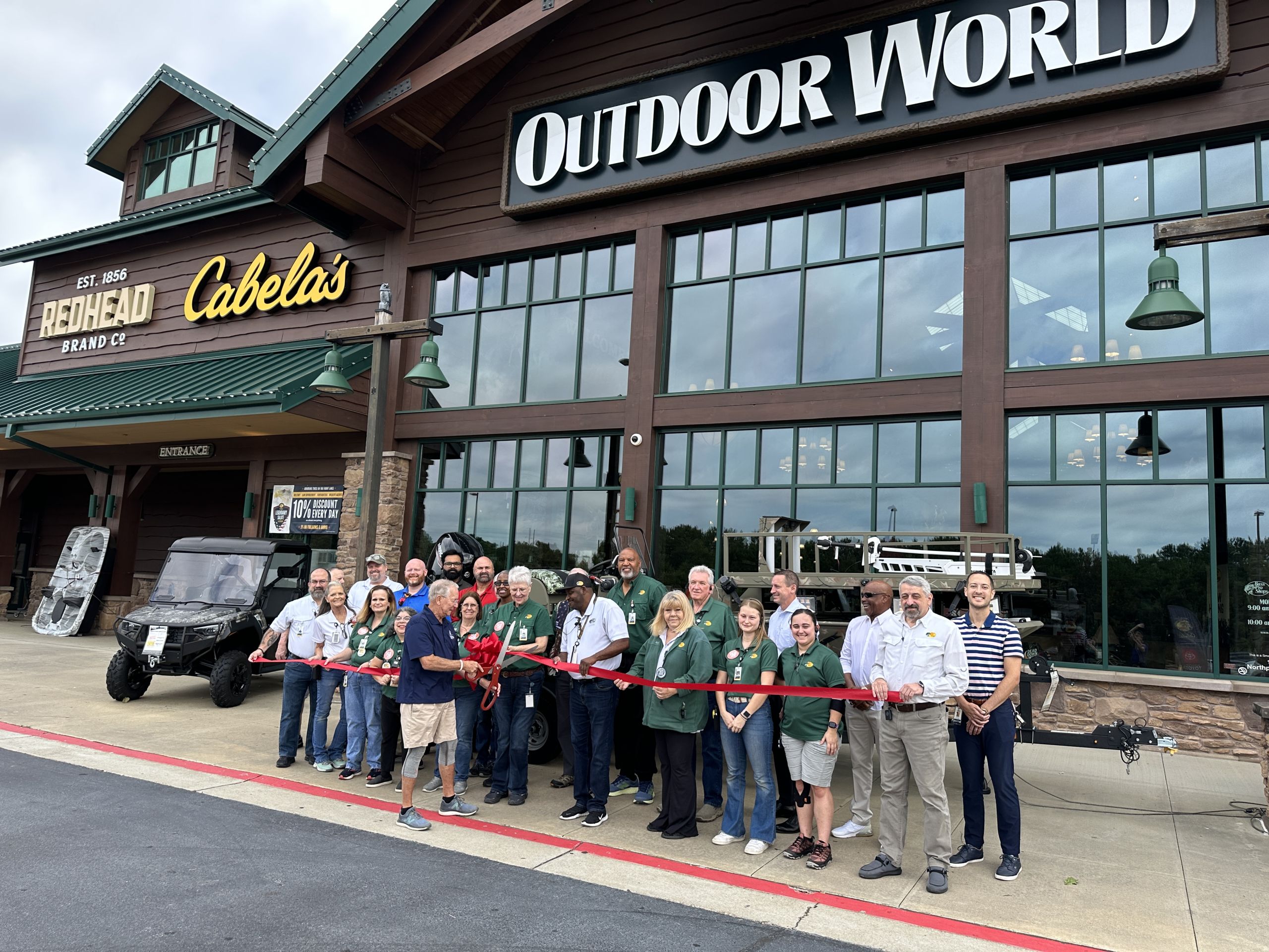 Image a group of people at a ribbon cutting outside of a large building