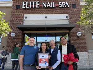 Four people standing in front of Elite Nail Spa. One person holds a "Best of 2024" award plaque.