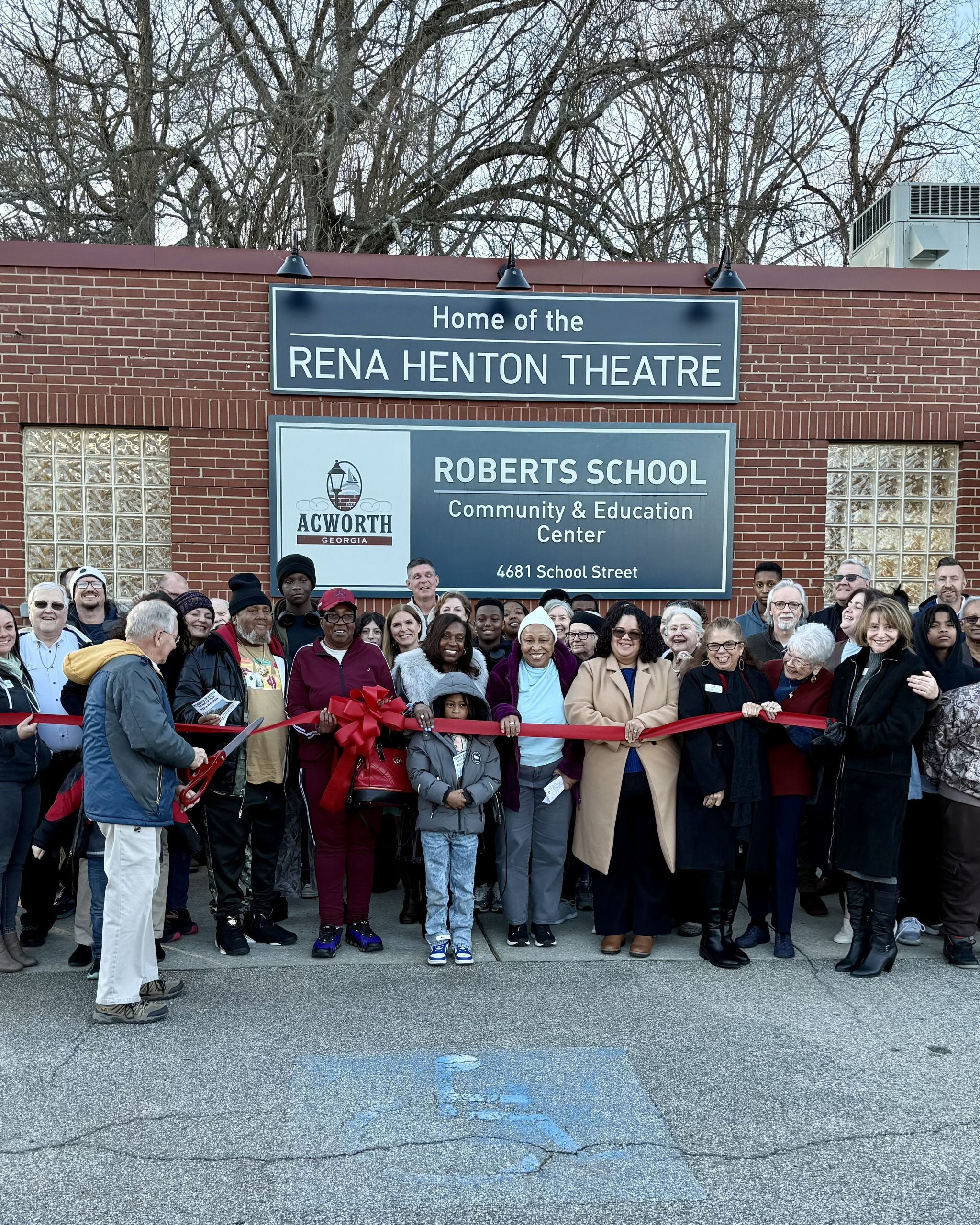 A large group of people gathers in front of the Rena Henton Theatre and Roberts School Community Center in Acworth for a ribbon-cutting ceremony celebrating Black History.